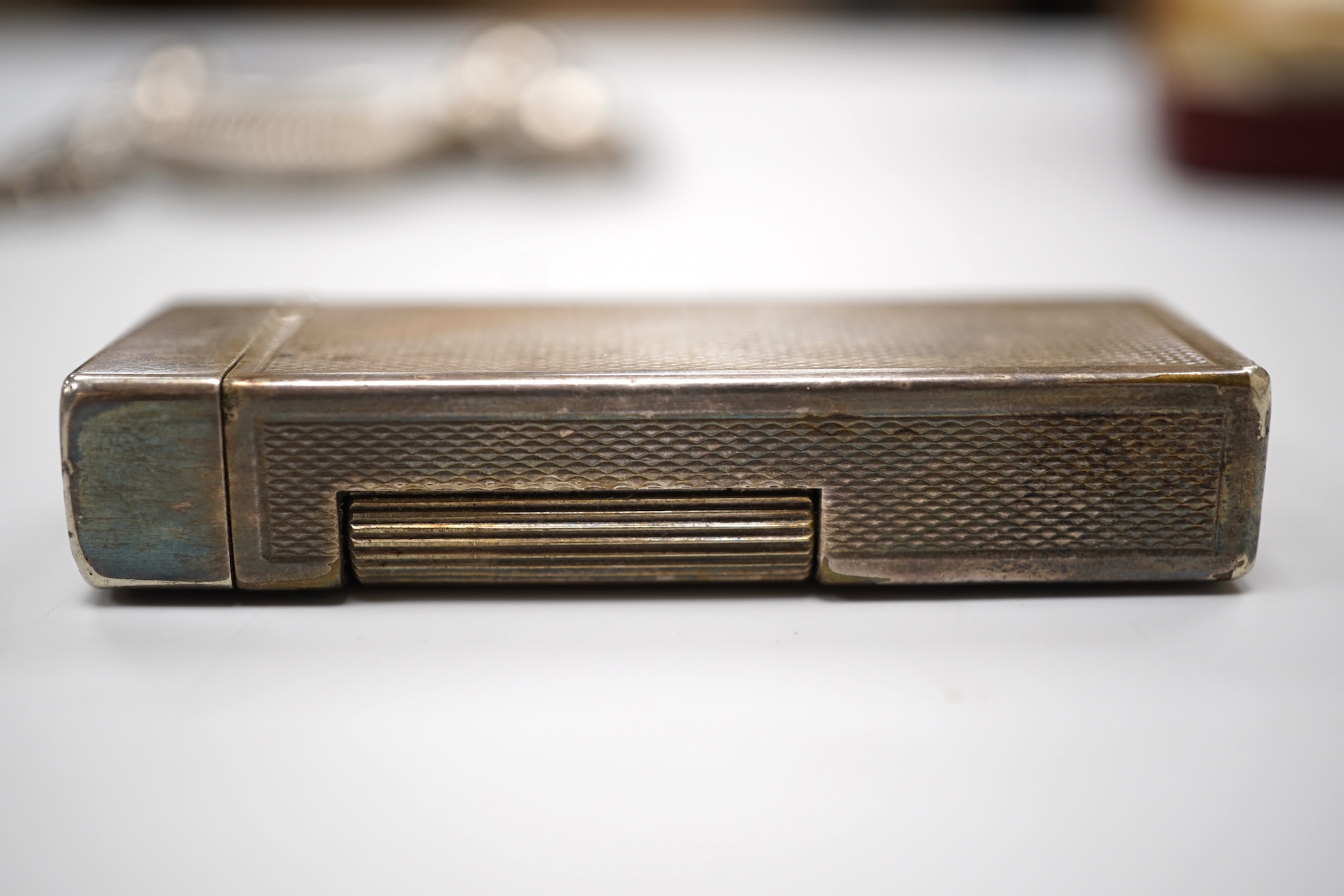An early 20th century white metal oval locket, 40mm, on a silver chain, a silver plated Dunhill lighter, in Dunhill box, a white metal cased manual wind wrist watch and a tortoiseshell purse.
